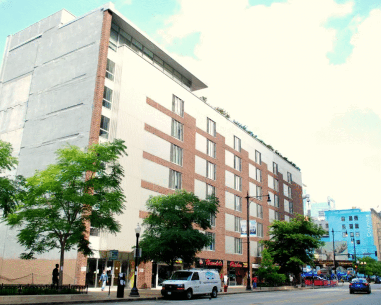 Modern apartment building with retail at the base and vehicles parked in front