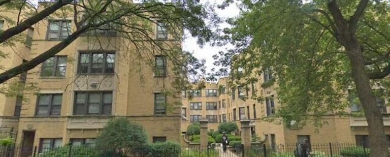 Brick apartment buildings with trees and a gated entrance
