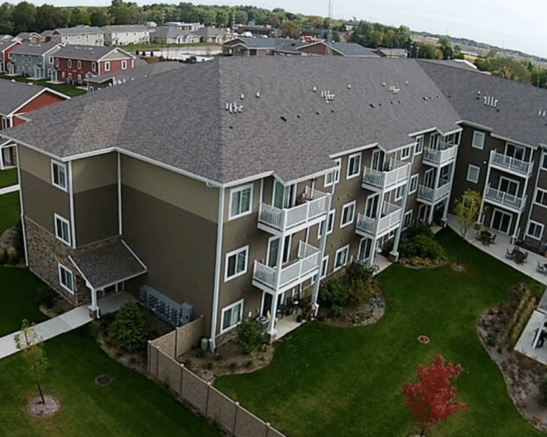 Three-story apartment complex surrounded by grass and walkways