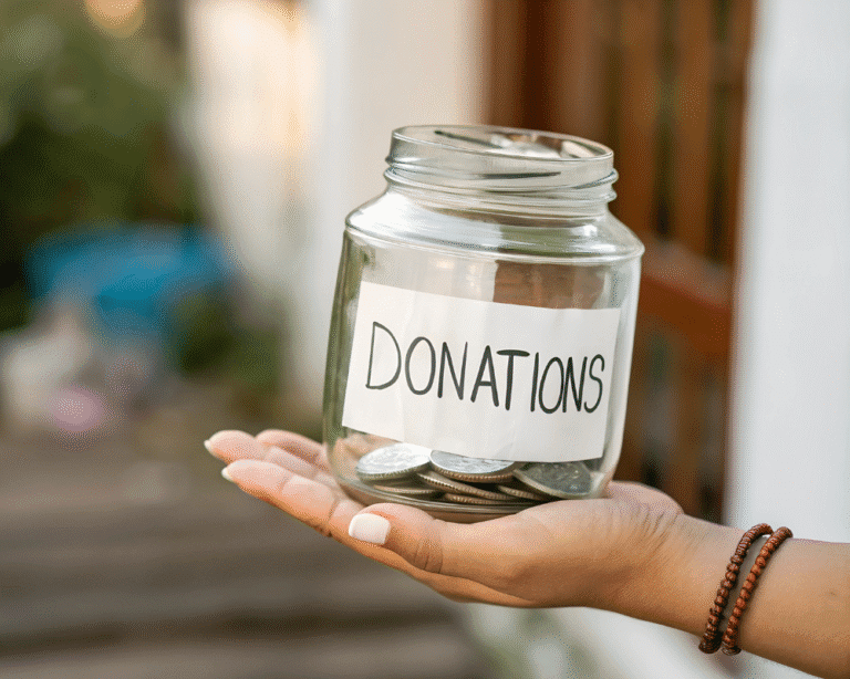 Hand holding a jar labeled 'Donations' filled with coins.