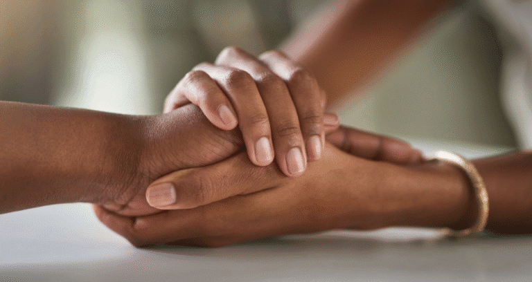 Hands gently holding another's hand in support