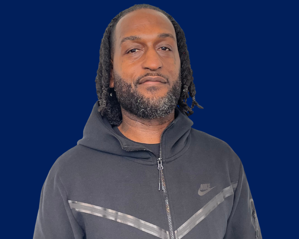 Portrait of a man in a black hoodie against a blue background