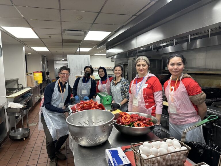 Group of volunteers preparing food in a large kitchen with peppers and eggs.