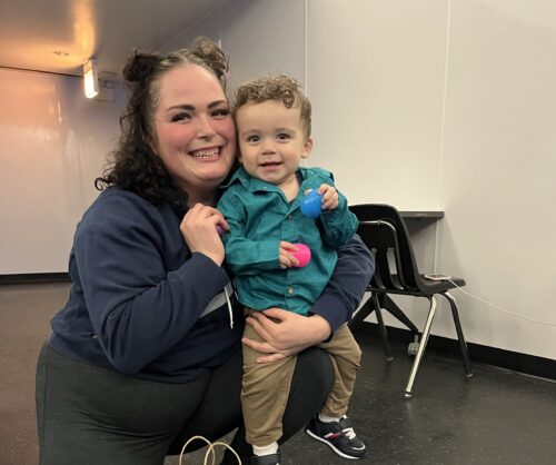 Smiling woman holding a young child with Easter eggs in hand
