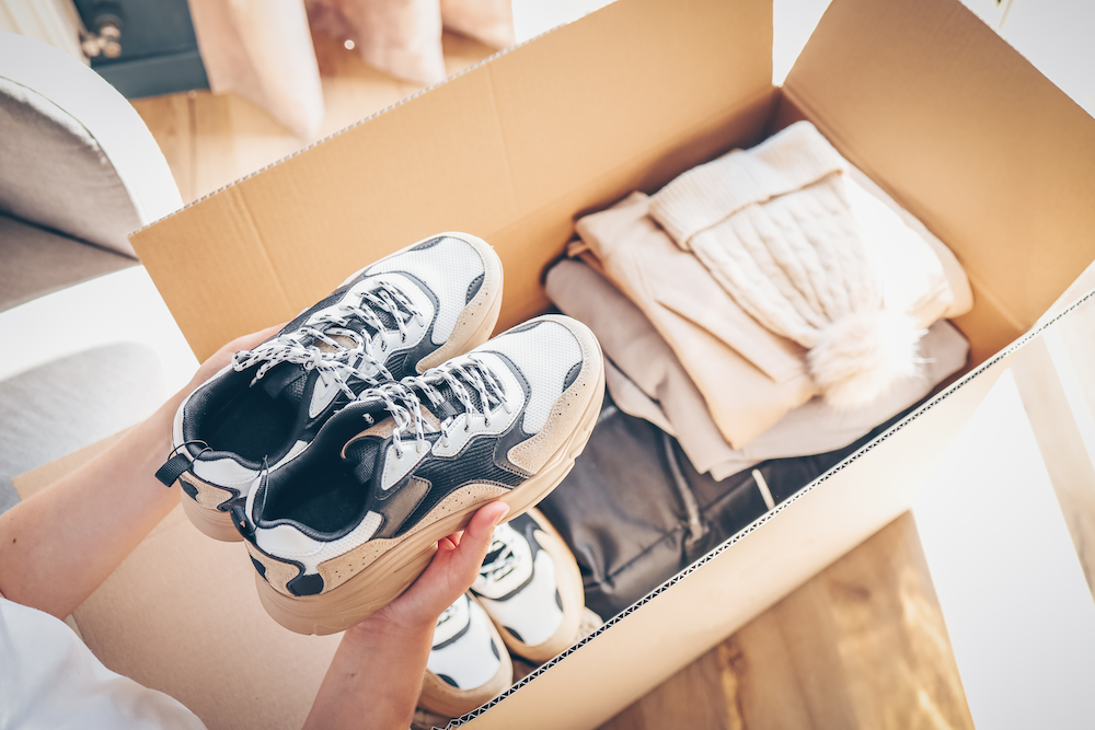 Hands holding sneakers above donation box