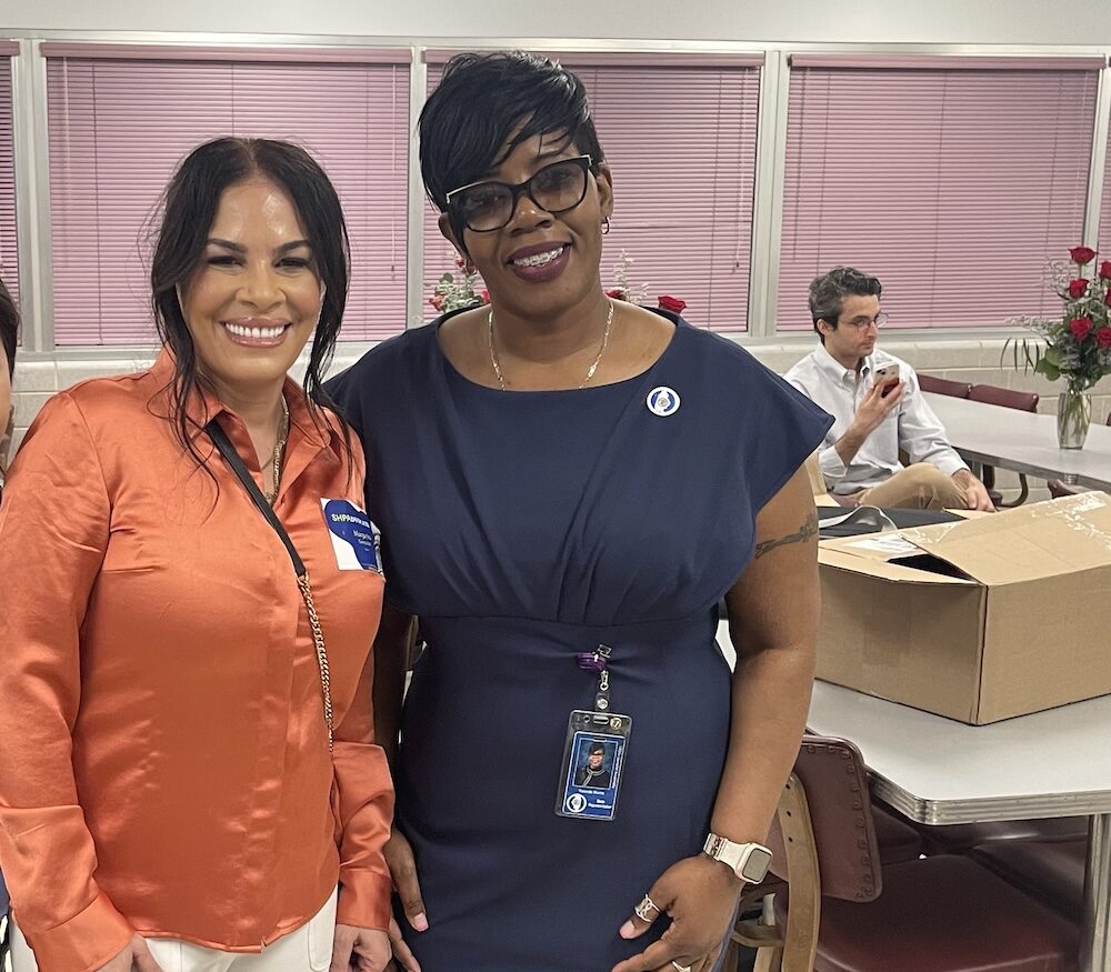 Two women smile at a community event.
