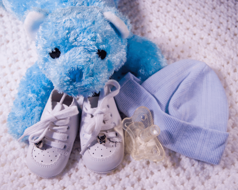 Baby essentials including shoes, pacifier, blue hat, and teddy bear