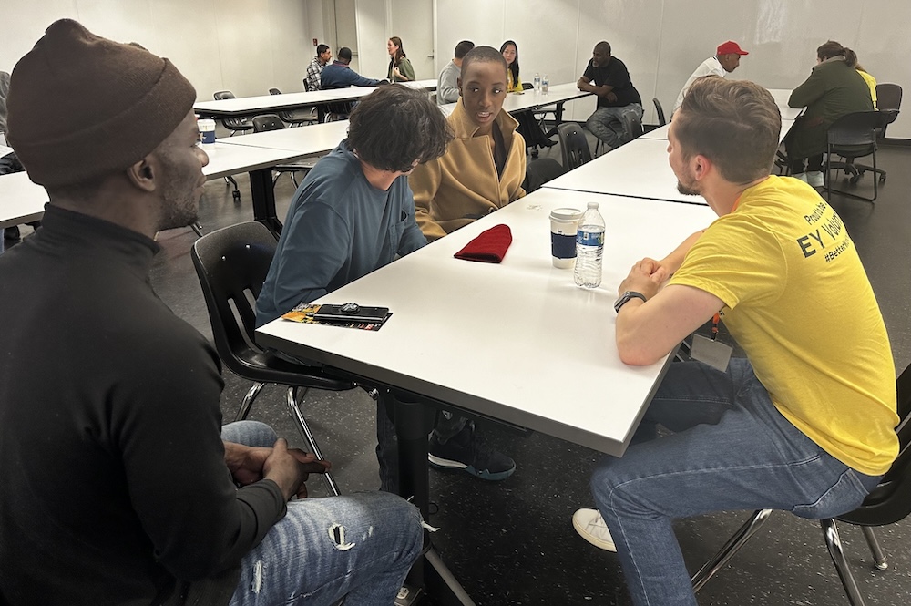 Volunteers in conversation with clients at a table.
