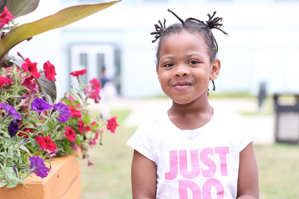 Smiling young girl next to vibrant flowers