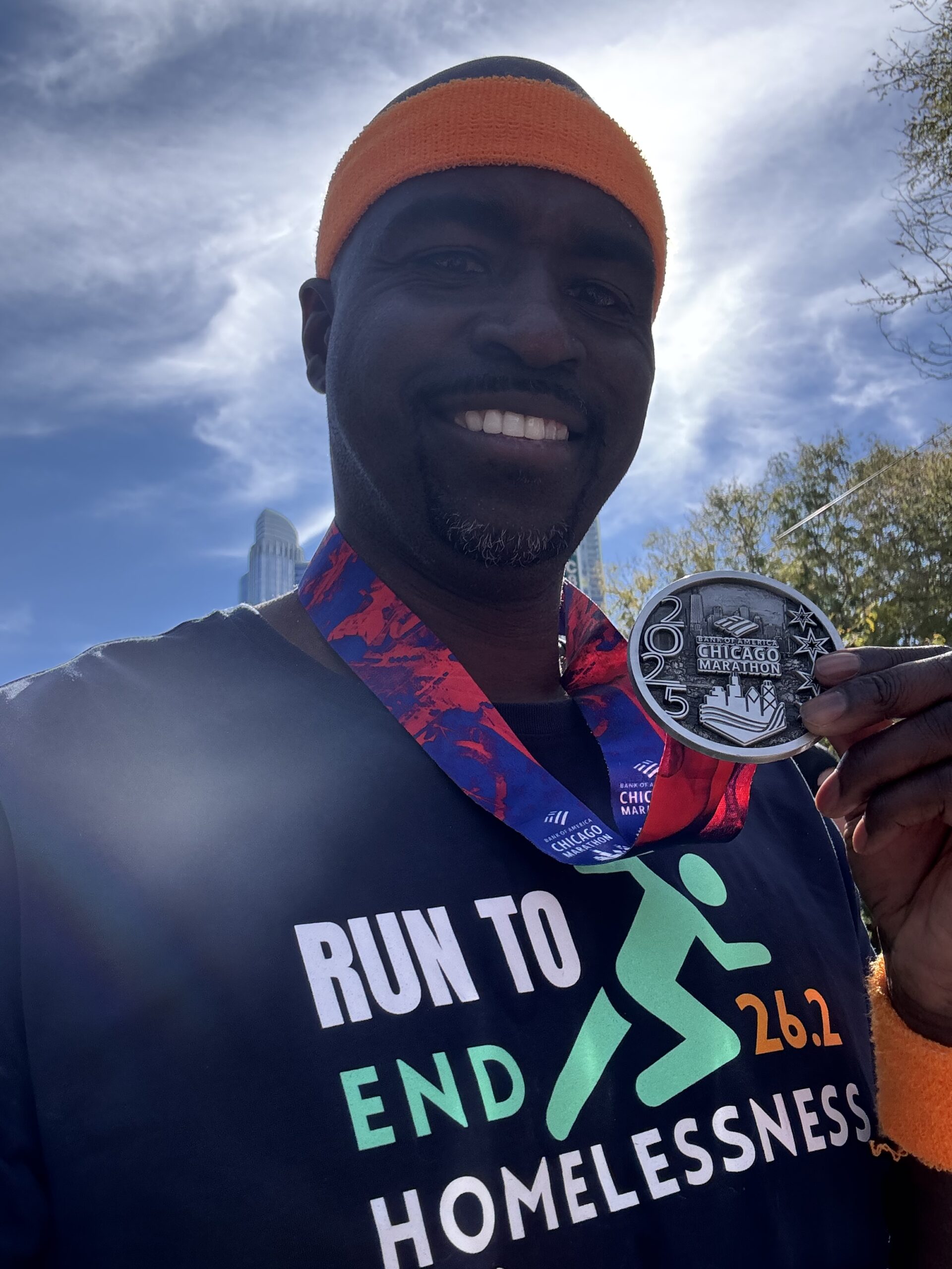 Anthony Spaulding celebrates at the Chicago Marathon finish line wearing his Team Run to End Homelessness shirt.