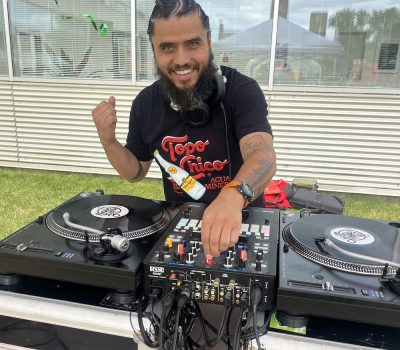 DJ smiling while playing music outdoors under a tent