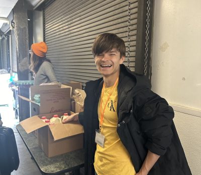 Young volunteer smiling while helping distribute goods in loading area