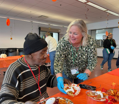 Staff member smiling and handing food to client at Thanksgiving event