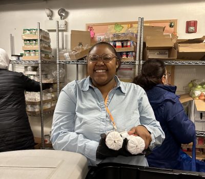 Woman smiling while holding two wrapped food items in pantry setting