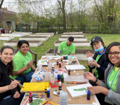 Volunteers seated outside painting garden signs