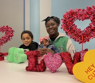 Mother with two children smiling surrounded by Valentine decorations