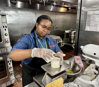 Young woman in chef attire pouring ingredients in a kitchen