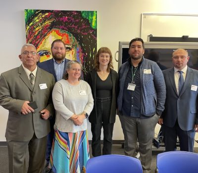 Group of people dressed professionally standing together in front of colorful art