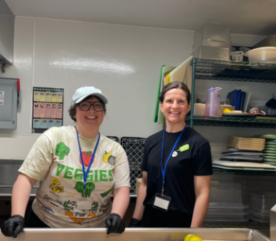 Two volunteers smiling in a kitchen